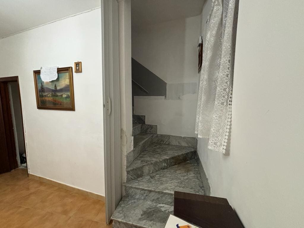 Staircase interna in marmo con scale in pietra naturale, all’interno di un appartamento con pareti bianche e decorazioni semplici, ambienti luminosi e accoglienti.