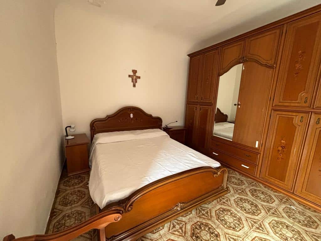 Letto matrimoniale in legno con aria classica e comfort, armadio grande con specchio integrato e design elegante, camera da letto accogliente con dettagli tradizionali, ideale per affitti e vendita immobili residenziali.