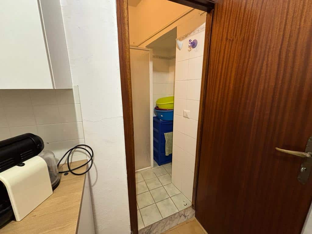Spazio lavanderia in appartamento con asciugamani colorati e spazio ottimizzato, ideale per la gestione delle faccende domestiche e il bucato quotidiano.