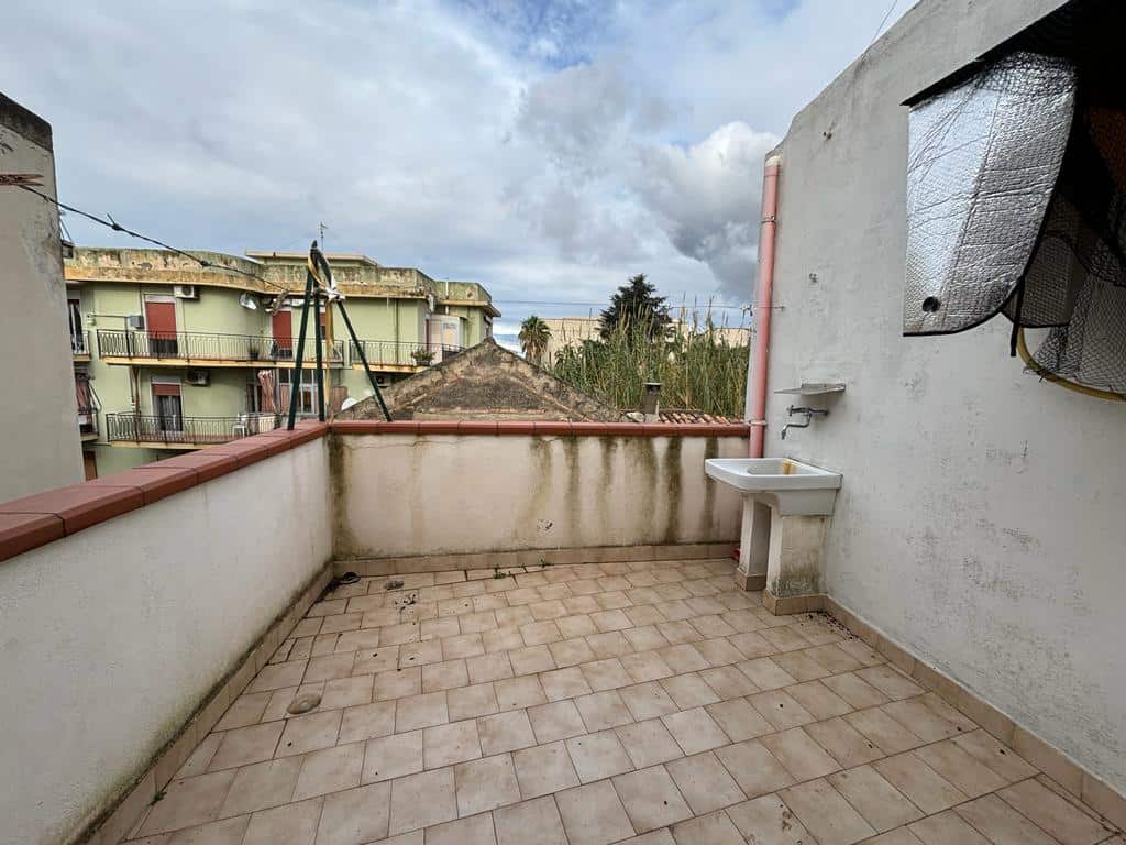 Balcone panoramico di casa con lavandino esterno e vista su edifici e natura, ideale per relax e attività all’aperto in contesti residenzialiNextCasa.
