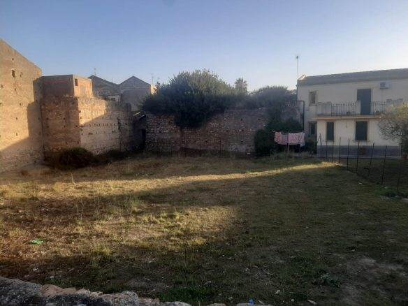 Prato di terreno con muri antichi e due case vicine, ambiente urbano con spazi all'aperto e verde, ideale per progetti di sviluppo immobiliare o giardini, in zona residenziale a NextCasa.