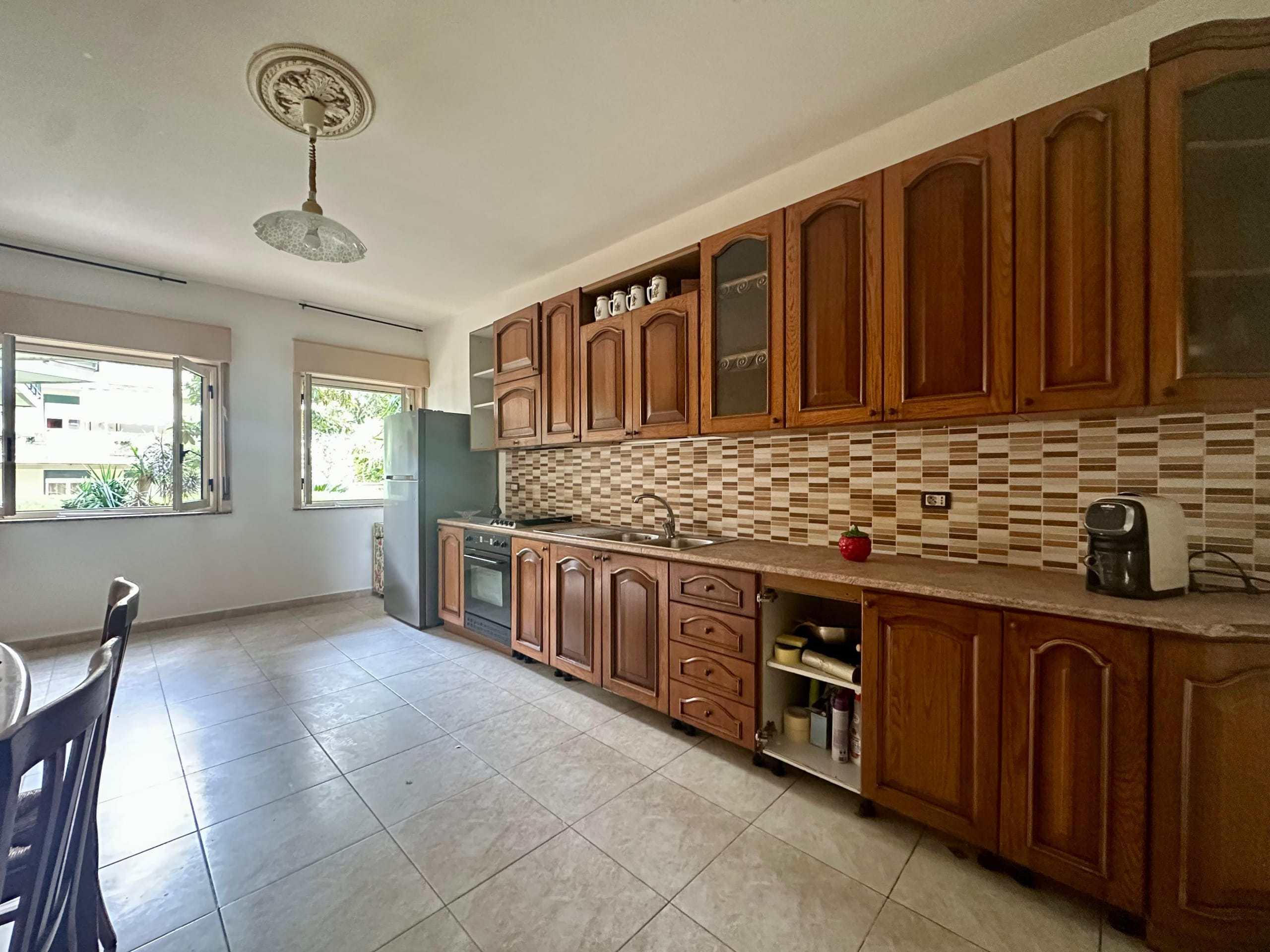 A3: Cucina spaziosa con mobili in legno, piano di lavoro in granito, e elettrodomestici moderni, perfetta per case in affitto e vendita a NextCasa.