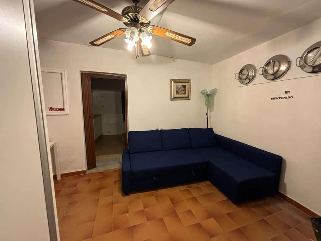 Divano angolare blu in soggiorno, soffitto con ventilatore e luci, pareti decorate con quadri e accessori metallici, ambiente accogliente, arredamento casa NextCasa, stile semplice e funzionale.