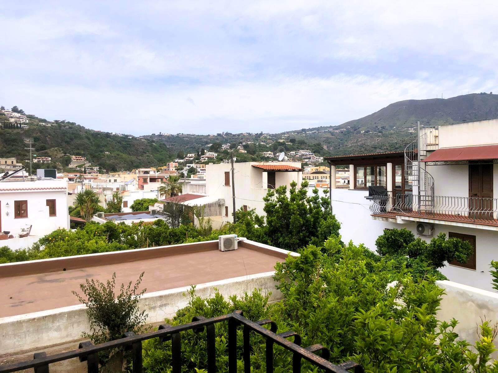 Vivace veduta di case mediterranee e ville con balconi soleggiati, circondate da alberi verdi e colline tranquille, in un suggestivo quartiere di Napoli, Italia.