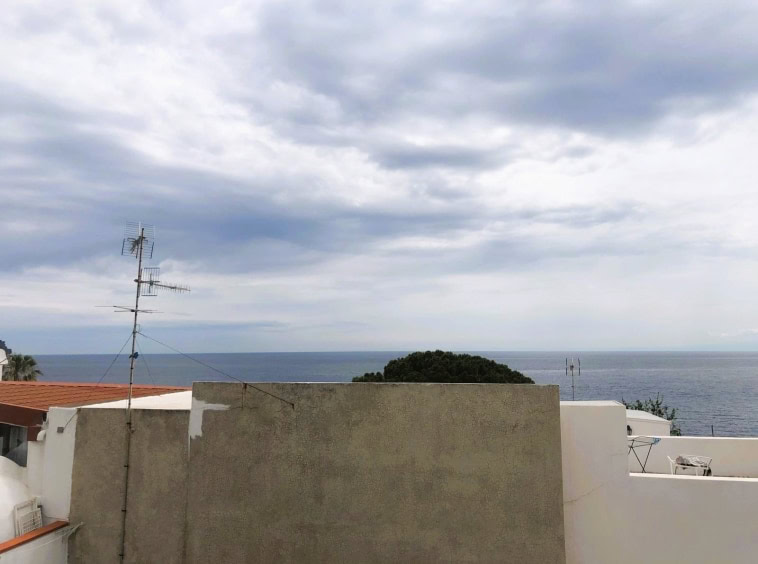 Vista mare dal terrazzo di un appartamento a NextCasa con cielo nuvoloso, condomini e antenne TV all'aperto, atmosfera tranquilla e rilassante in zona residenziale vicino alla costa.