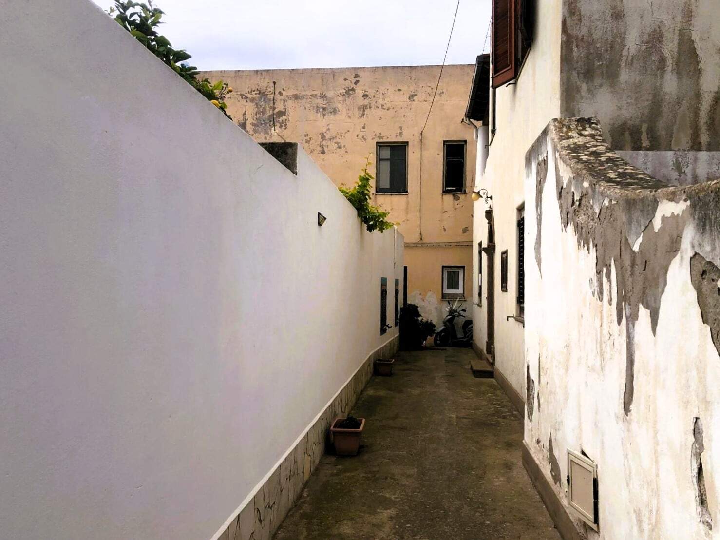 Vecchio vicolo di Napoli con muri di pietra e case caratteristiche, atmosfera autentica e suggestiva.