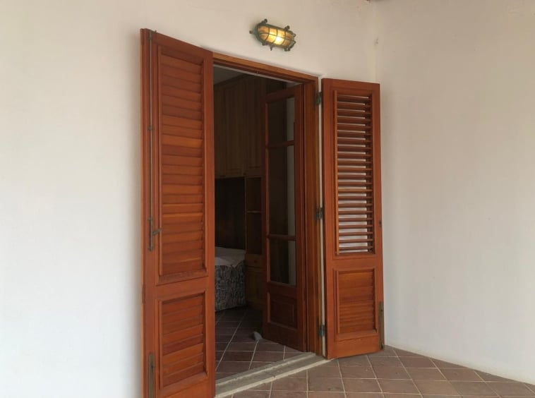 Persiane in legno su finestra e porta su terrazza in stile rustico, ufficio o zona soggiorno.