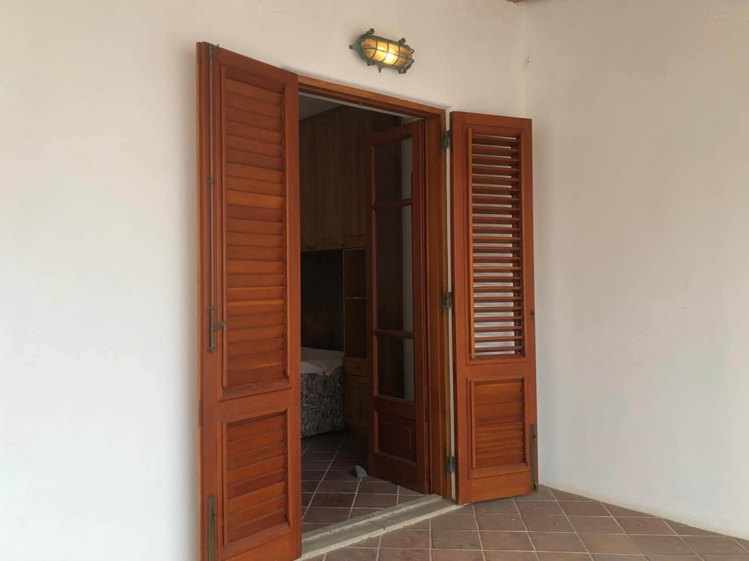 Persiane in legno su finestra e porta su terrazza in stile rustico, ufficio o zona soggiorno.