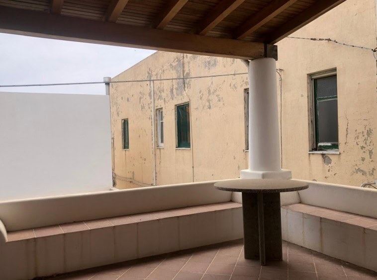 Balcone con vista su edificio storico con finestre, spazio esterno con seduta in muratura e colonnina, ideale per relax e godersi l'ambiente urbano in contesto residenziale.