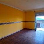 Spazio abitativo con pareti gialle e balcone, ideale per la vendita e affitto di immobili residenziali.