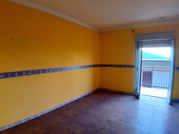 Spazio abitativo con pareti gialle e balcone, ideale per la vendita e affitto di immobili residenziali.