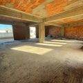 Luminoso interno di un appartamento in costruzione con pareti in mattoni e struttura di cemento, pronto per imbiancatura e finiture.