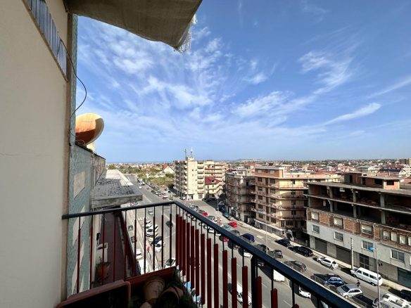 VISTA PANORAMICA dal BALCONE di un APPARTAMENTO in città, con VILLETTE, UFFICI e STRADE trafficate, cielo azzurro e nuvole. Ottima opportunità di investimento immobiliari NextCasa.