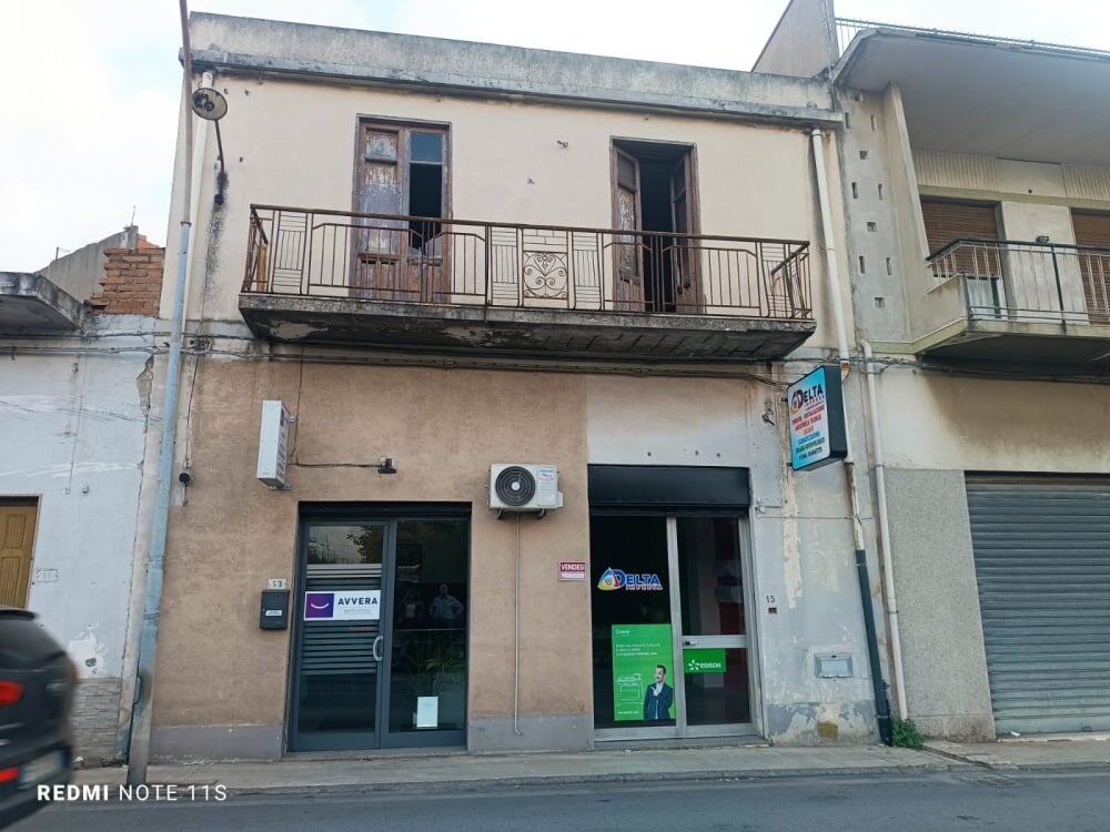 Vecchio edificio residenziale con balcone e negozi al piano terra, commerciale, ufficio, o deposito, extralusso, in centro città, Italia, facciata dismessa e deteriorata, pareti rovinate, struttura in cattive condizioni.