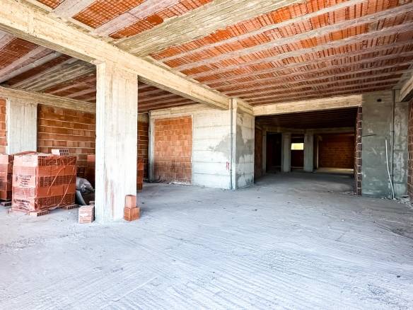 Finestra di un appartamento in costruzione con pareti in mattoni e struttura in cemento, pronto per lavori di finitura, ambiente spazioso e luminoso.