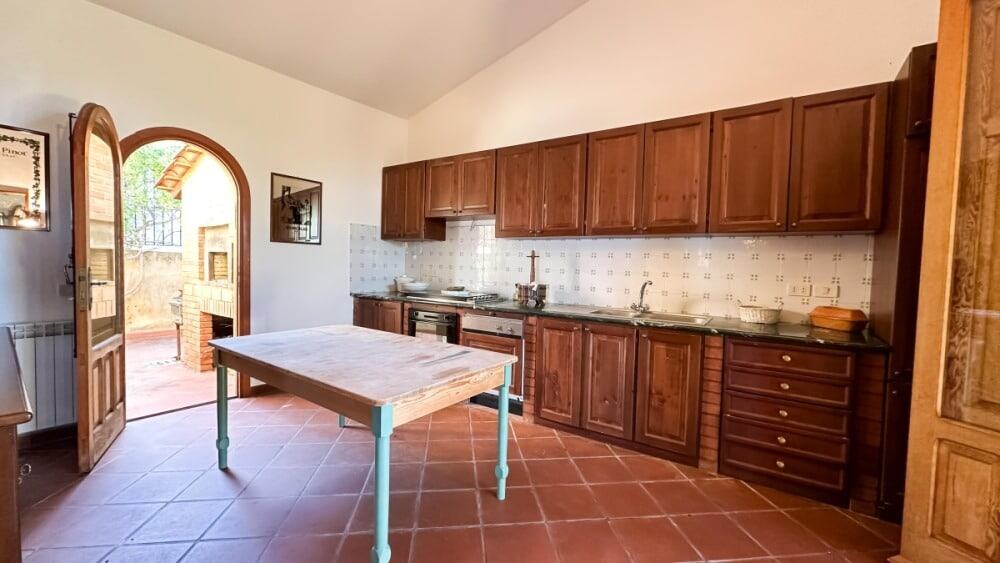 Prodotto di cucina rustica con mobili in legno e cucina funzionale, ambiente accogliente e tradizionale. Cucina spaziosa con ampio piano di lavoro, forno, lavello e accessori in stile classico.