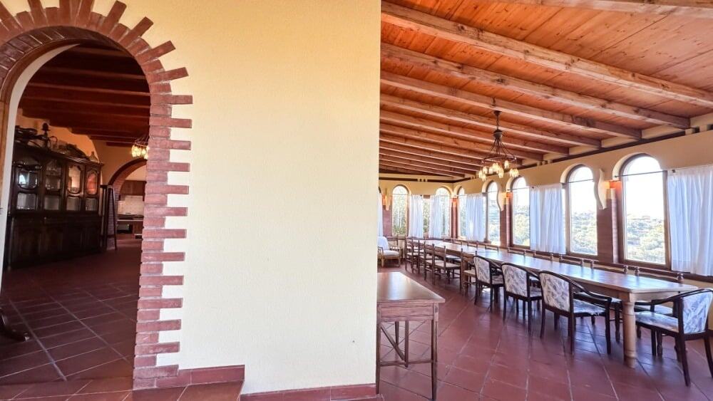 Ampia sala ristorazione con soffitto in legno e grandi finestrone, ambiente accogliente e luminoso, perfetto per eventi e incontri, a NextCasa.