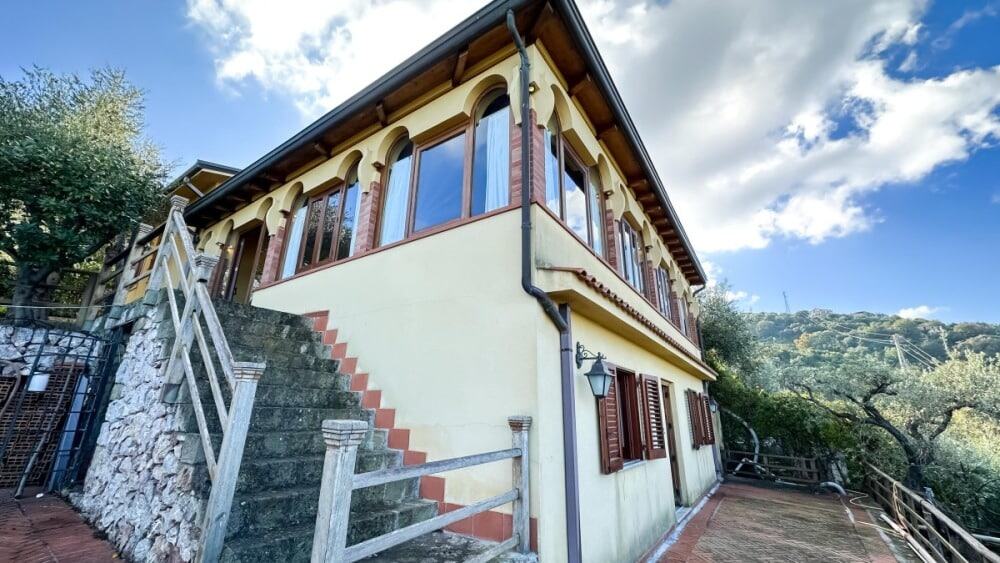 Villetta bifamiliare in collina con vista panoramica e giardino, ideale per investimento immobiliare e case vacanza in Italia. Architettura tradizionale e spazi esterni accessoriati.