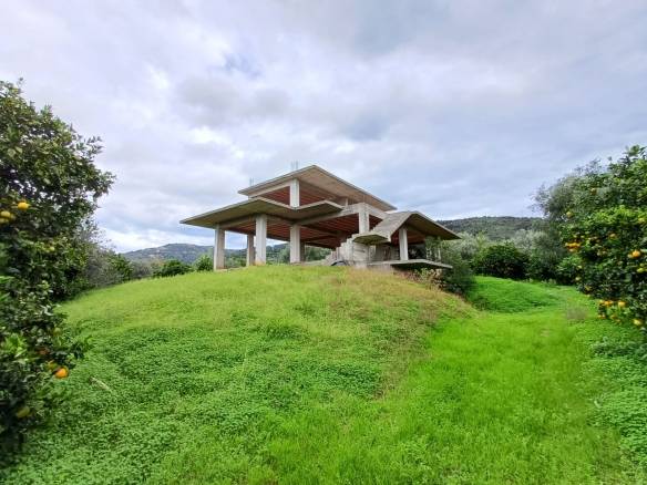 Casa moderna in costruzione su collina con vista panoramica sui campi e sulle montagne circostanti, in un contesto naturale e tranquillo.