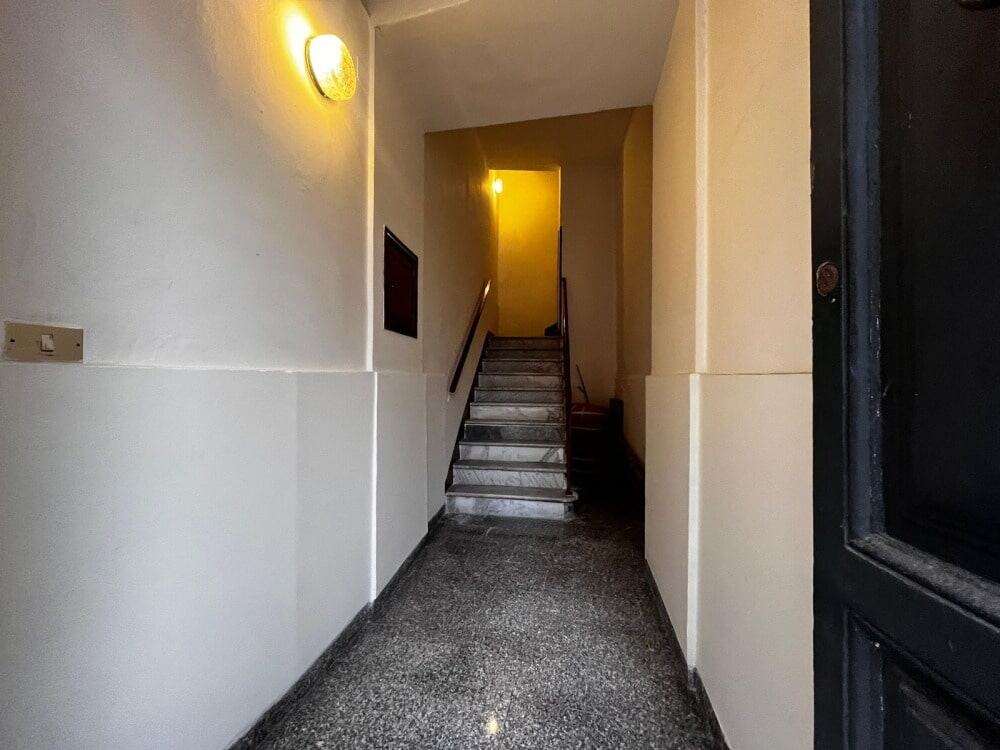 Scala condominiale con ringhiera in metallo e illuminazione warm, area di ingresso moderna e funzionale.
