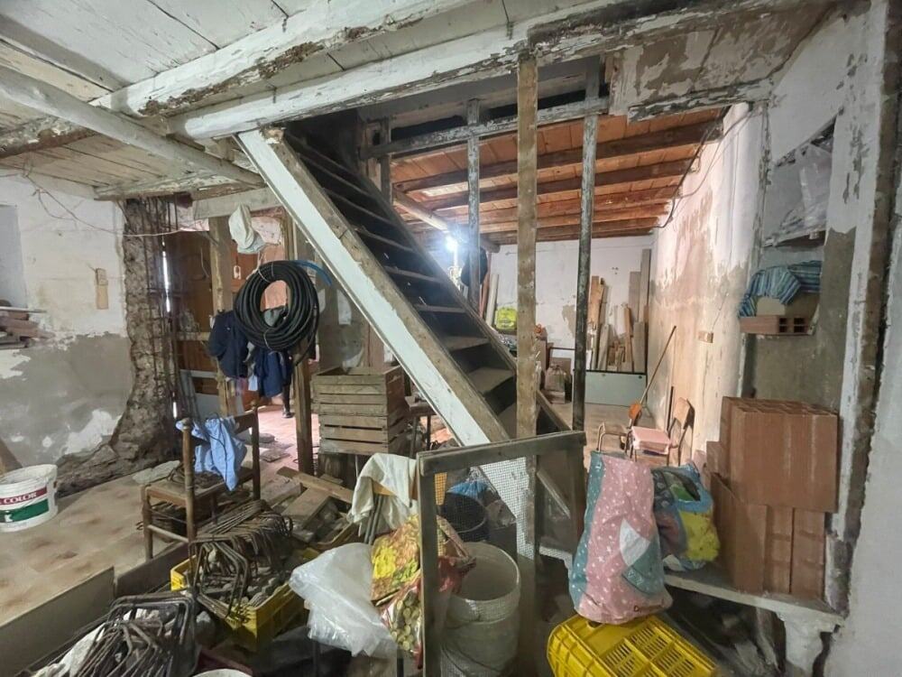 Vecchio stabile in ristrutturazione con scale in metallo, muri in pietra e materiali da costruzione sparsi, ambiente di lavoro per ristrutturazioni edilizie, immagini di cantiere edilizio.