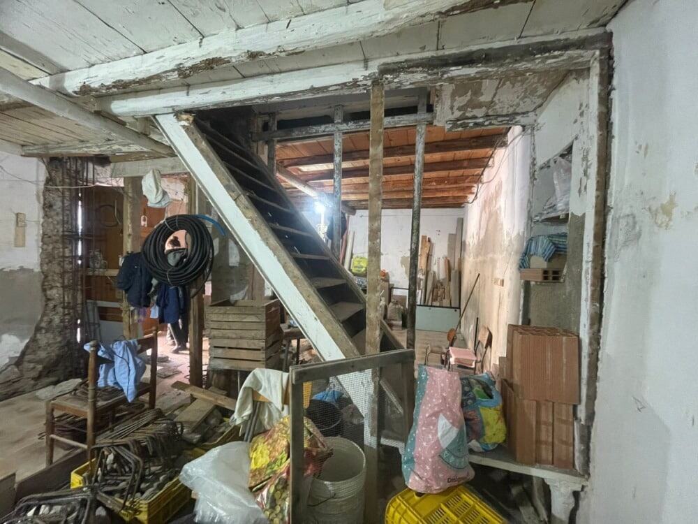 Vecchio spazio di ristrutturazione con materiali da costruzione e scaffali di legno, ambiente interno in fase di rinnovamento, aspetto rustico e industriale, ideale per progetti di ristrutturazione casa.