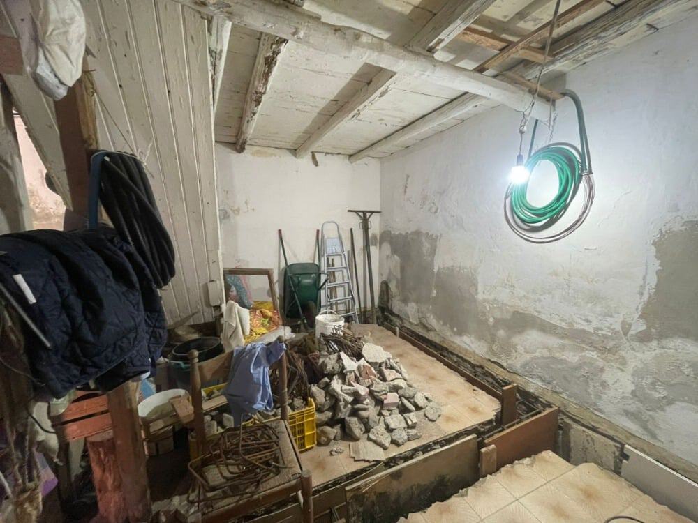 Cantiere di ristrutturazione in una soffitta con strumenti da lavoro, pietre e materiali per rinnovare lo spazio, illuminato da lampada a soffitto e attrezzature di bricolage.
