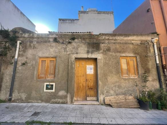 Vecchio edificio in vendita con finestre in legno e porta centrale, situato in zona urbana, foto di una struttura da ristrutturare, ideale per investitori e progetti di restauro, con ambiente esterno e caratteristiche storiche.