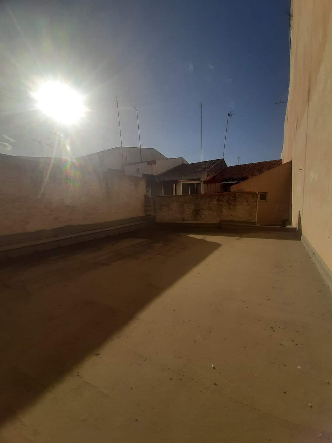 Techo di un terrazzo soleggiato con vista sul cielo blu e sui tetti delle case vicine, ideale per ristrutturare e personalizzare uno spazio esterno in un contesto residenziale.