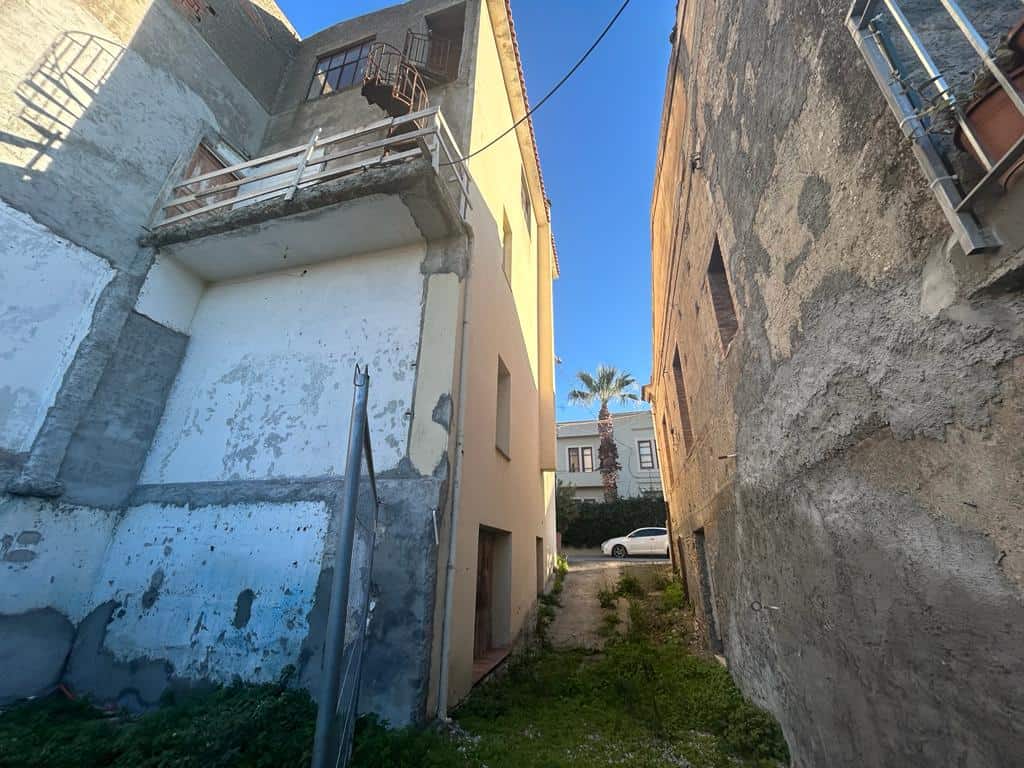 Vecchio edificio in fase di ristrutturazione, cortile interno con spazio verde e accesso pedonale, situato in zona urbana, luce solare naturale.