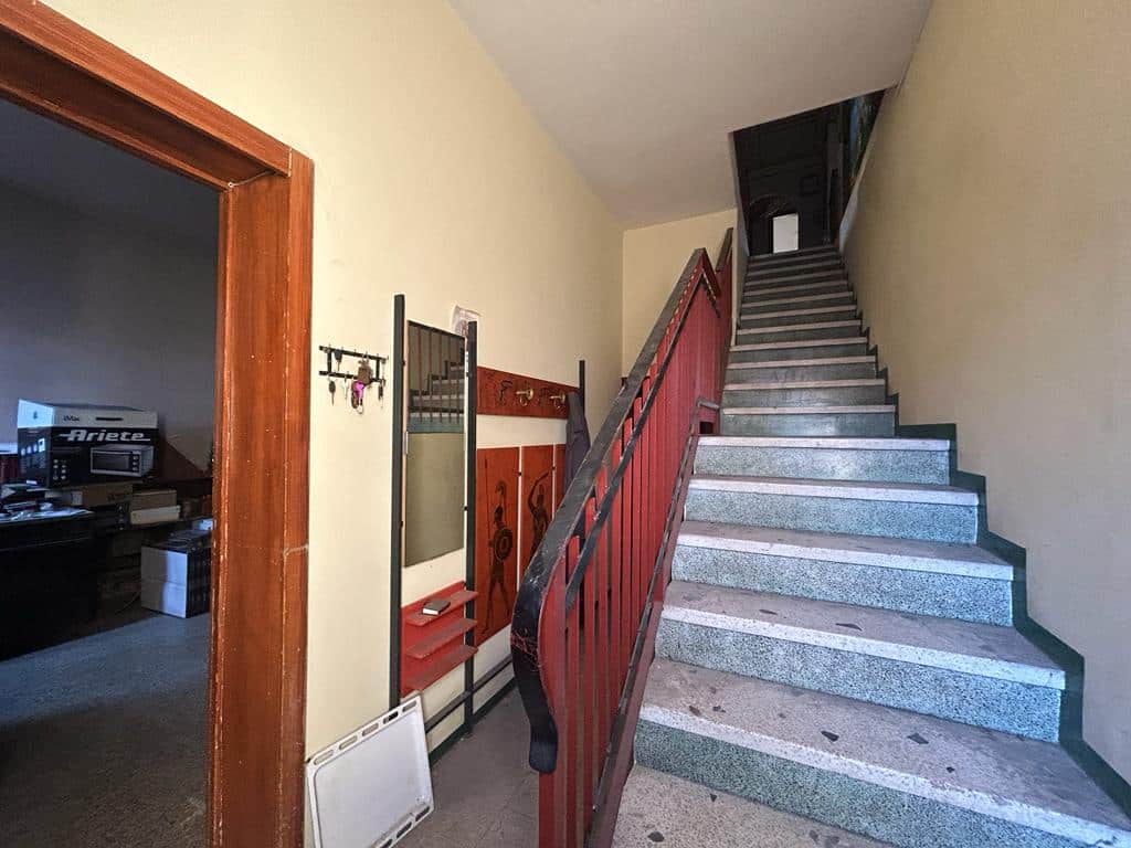 Scala interna con ringhiera in metallo e gradini in pietra, ingresso all'abitazione, stile classico e funzionale.