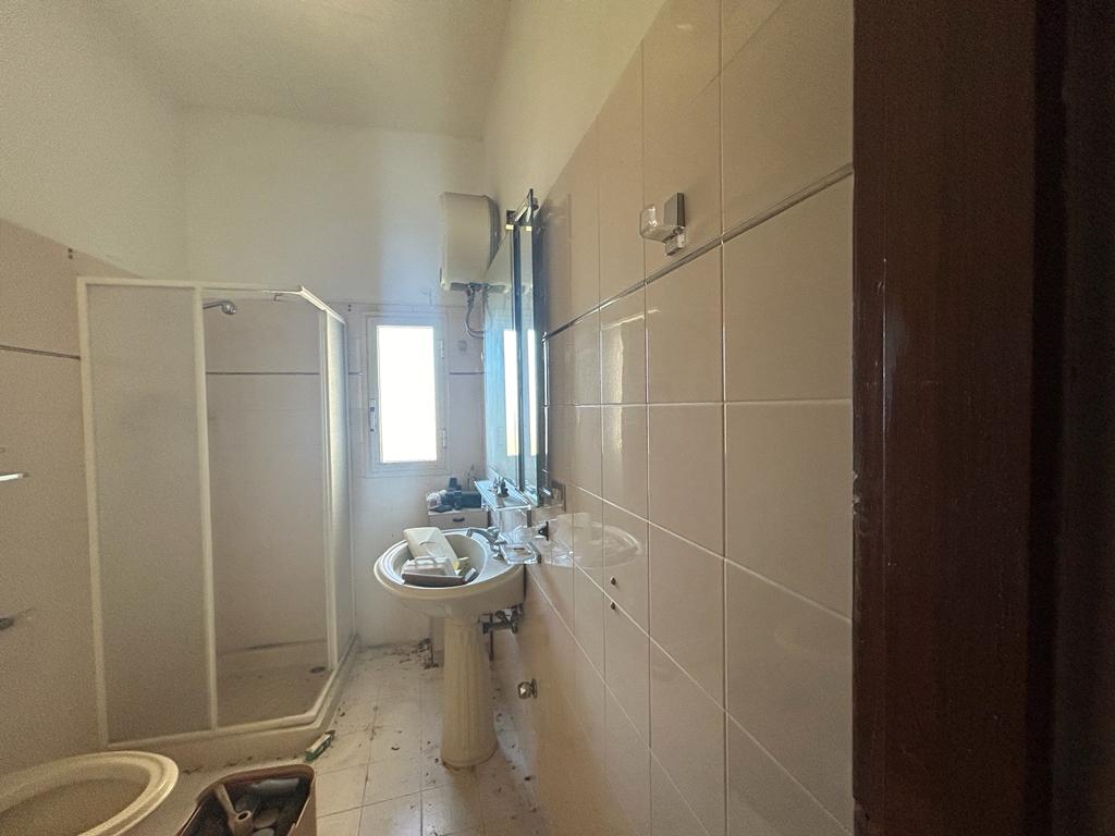 Vecchia casa bagno con doccia e lavabo, luci naturali, soluzione abitativa da ristrutturare, NextCasa Italia.