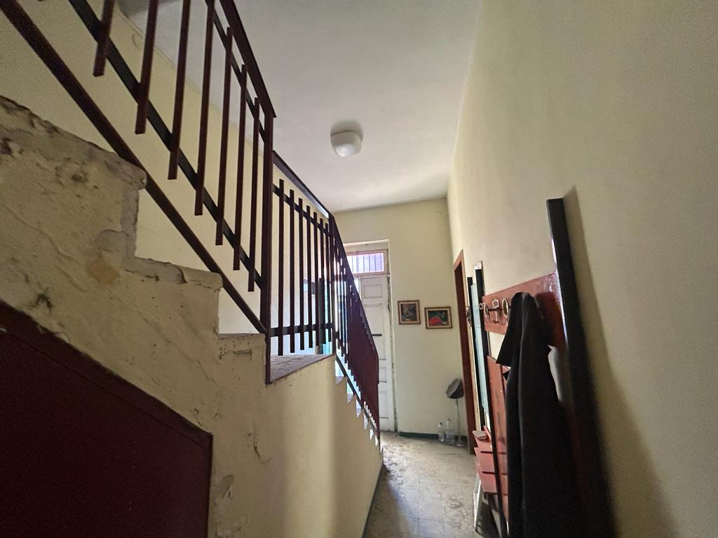 Scala interna in stile tradizionale, zona di ingresso di casa, dettagli di arredo e decorazioni, con pareti chiare e finestra luminosa, coronata da un soffitto con lampada centrale.