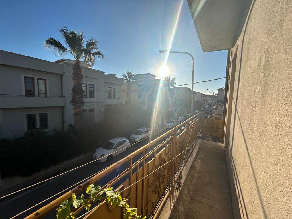 Balcone soleggiato in zona residenziale con vista su palme e strada, ideale per relax e spazi all'aperto.