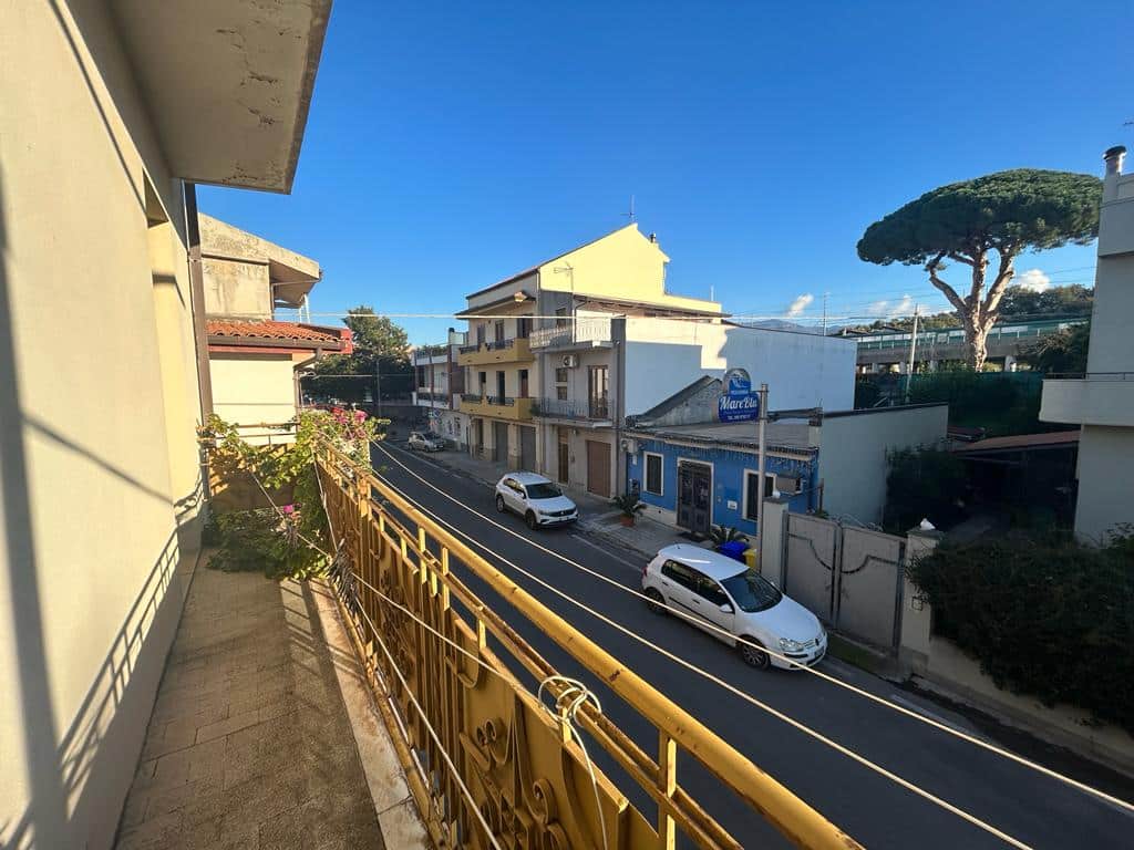 Balcone di un appartamento nella zona residenziale con vista sulle strade di mare, auto parcheggiate e edifici colorati, ideale per chi cerca soluzioni immobiliari a NextCasa in Italia.