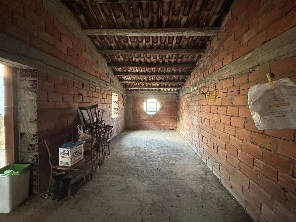 Ampio ambiente in costruzione con pareti in mattone rosso e soffitto in legno, vista naturale e illuminazione da finestra rotonda, ambiente nomevole da ristrutturare e personalizzare.