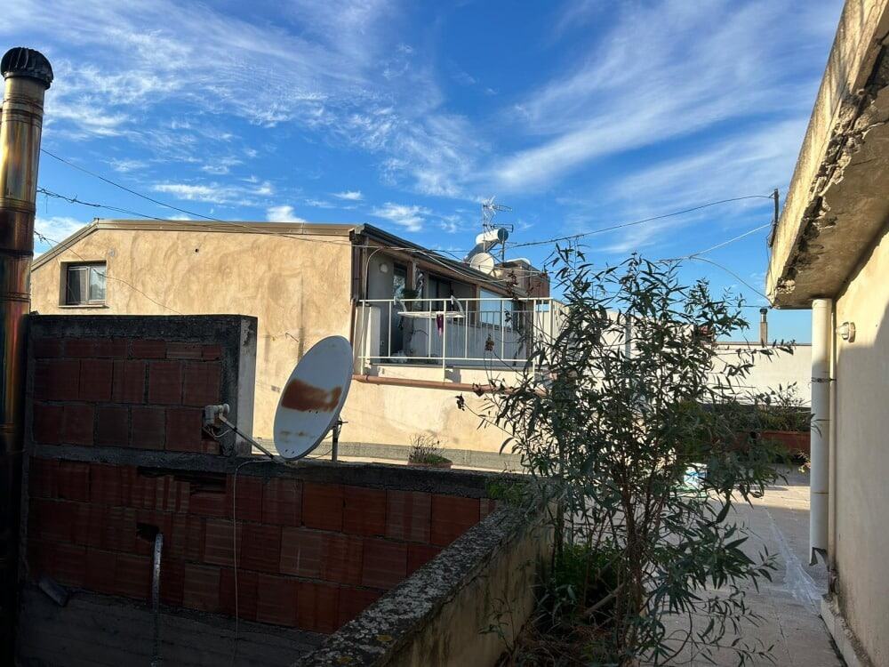 Satellite antenna e terrazza con vista su edifici residenziali in zona urbana soleggiata.