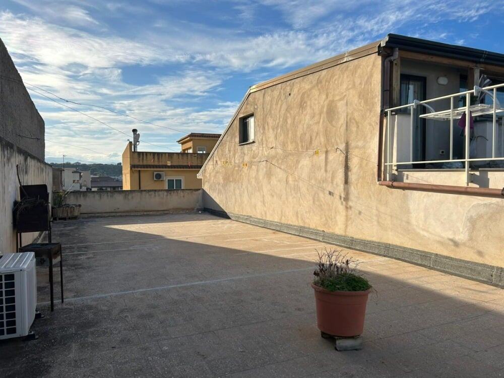 Ampio terrazzo all'aperto con vista panoramica e spazio per relax, con piante e area lavanderia, ideale per vivere all'aperto e godere della luce naturale.