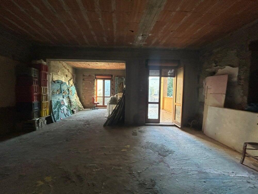 Vano in fase di ristrutturazione con pareti in pietra e grandi finestre, pronta per essere trasformata in un accogliente spazio abitativo o ufficio, ideale per ristrutturatori e investitori immobiliari.