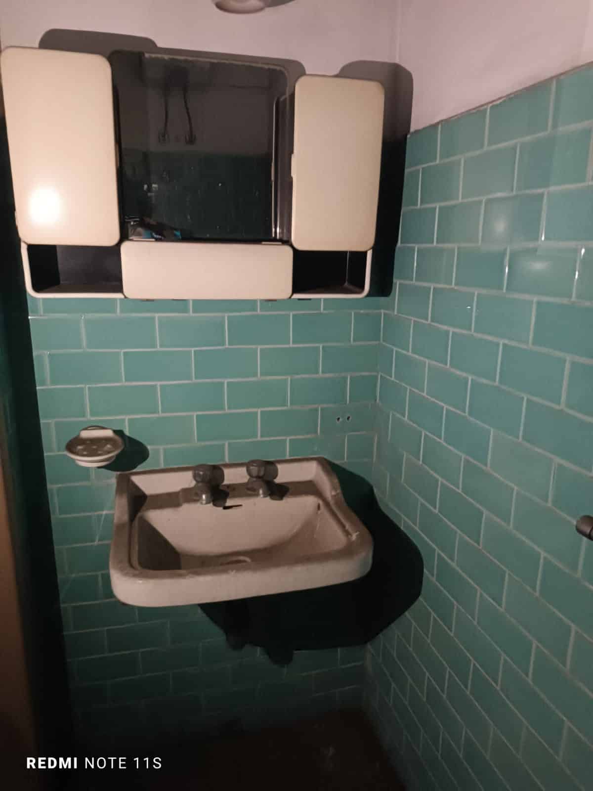 Lavabo vintage con specchio e piastrelle in stile retrò, ideale per ristrutturare il bagno con comfort e stile, perfetto per ambienti da valorizzare con mobili moderni o vintage.
