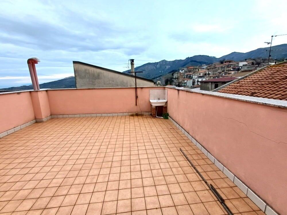 Terrazza panoramica con vista sulle colline e sui tetti di un quartiere residenziale, ideale per realizzare uno spazio esterno vivibile e accogliente.