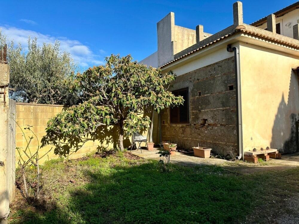 Vecchia casa in mattoni con giardino e alberi, pareti rinnovate e spazio esterno con piante ornamentali, ideale per investimenti immobiliari e ristrutturazioni, contattaci per più dettagli.