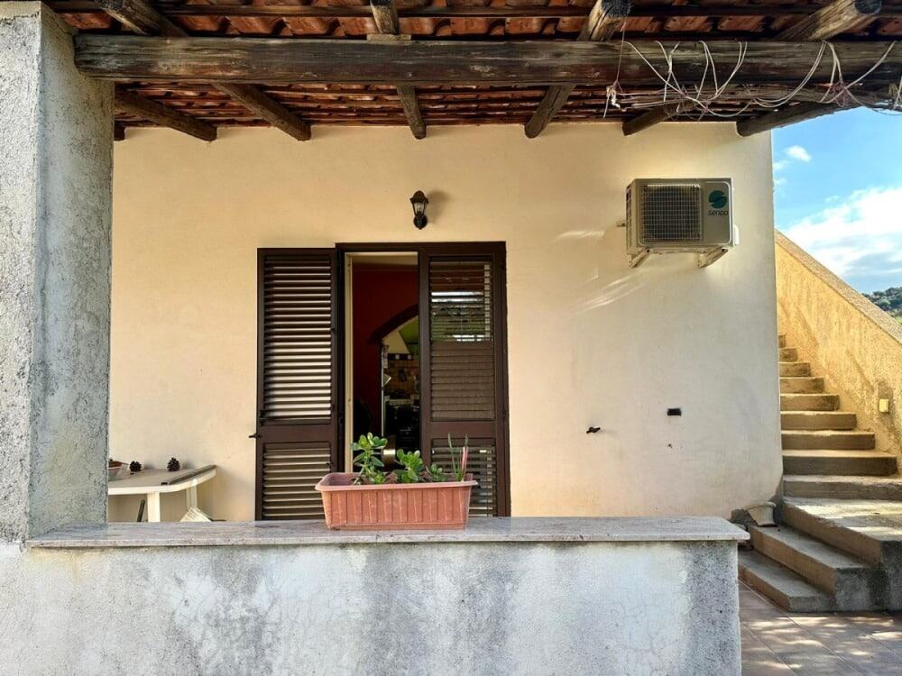 Balcone di casa con porta a persiana in legno, condizionatore e ambiente esterno accogliente, ideale per relax e affaccio sulla natura, rappresenta un esempio di arredamento esterno di proprietà immobiliari NextCasa, inserzioni di immobili in Italia.