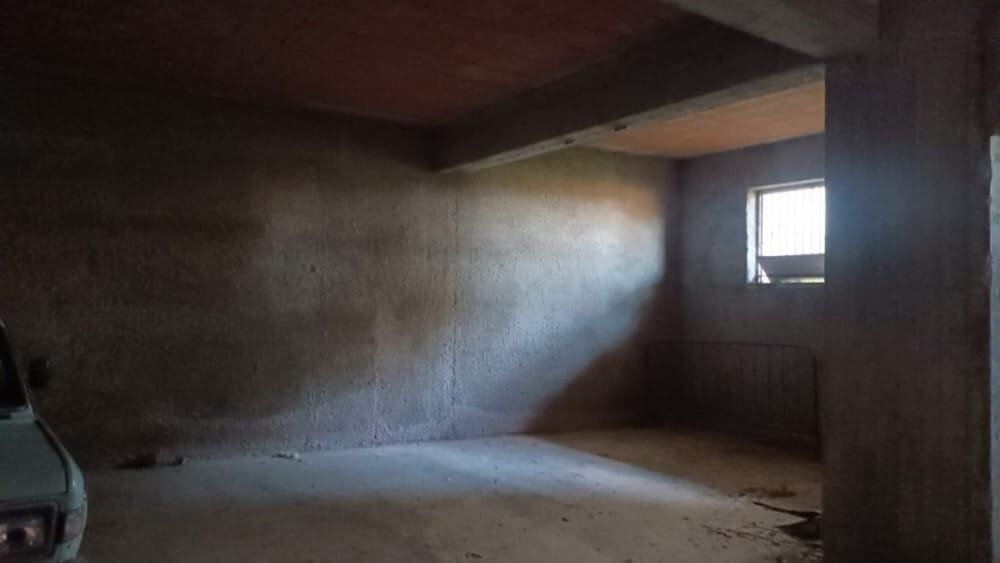 Cortile o garage in costruzione con pareti in cemento, finestra che lascia entrare luce naturale, pronto per finiture e personalizzazioni.