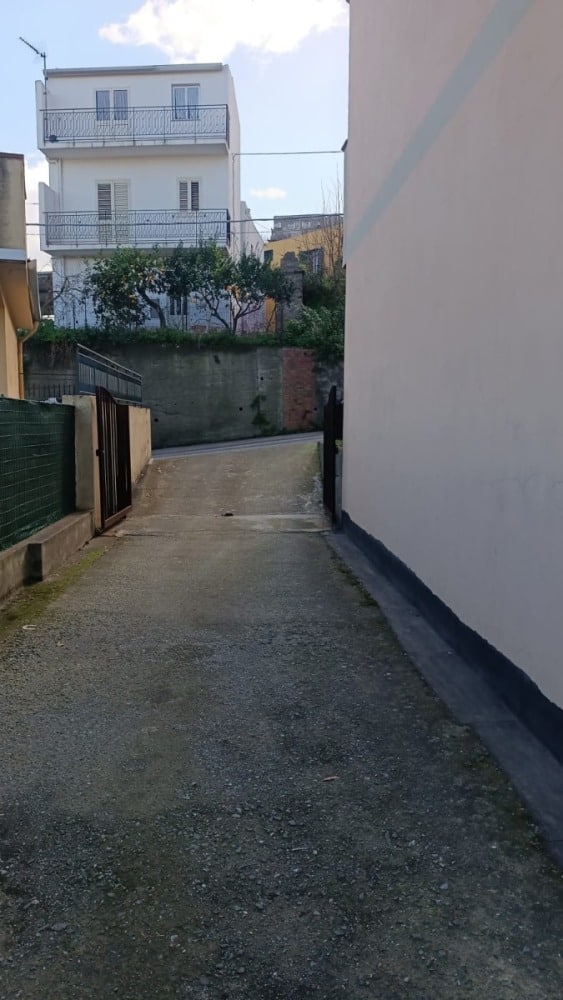 Scarpata con strada di accesso privata e barriere di sicurezza in zona residenziale Italia.