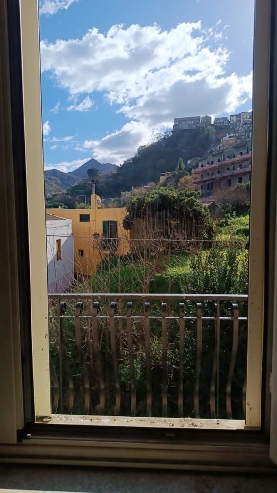 Vista panoramica di case colorate e montagna con cielo nuvoloso dall'appartamento NextCasa in vendita o affitto, ideale per chi cerca immobili con vista naturale e ambientazioni pittoresche.