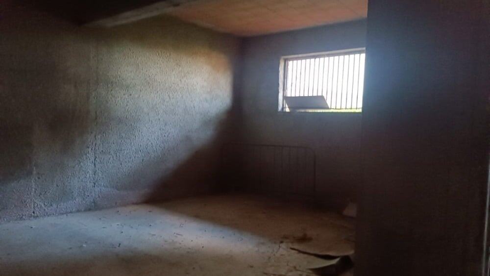 Nuova casa in costruzione con pareti in cemento grezzo e finestra con sbarre, ambiente da rifinire, ideale per progetti di ristrutturazione e personalizzazione, situata in una zona tranquilla.