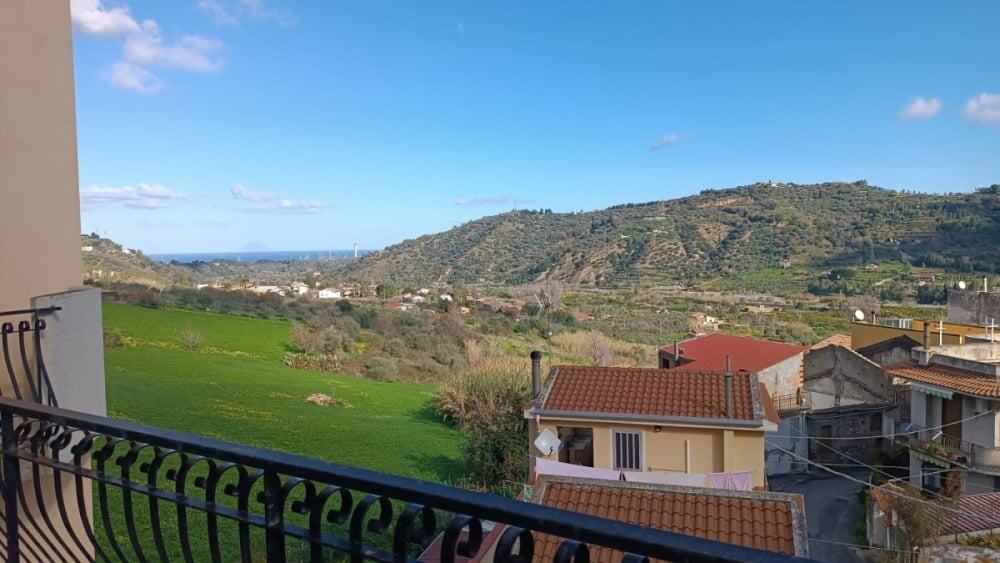 VISTA PANORAMICA dal balcone di case in collina con paesaggi verdi e mare in lontananza, ideale per immobili e investimenti immobiliari in Liguria.