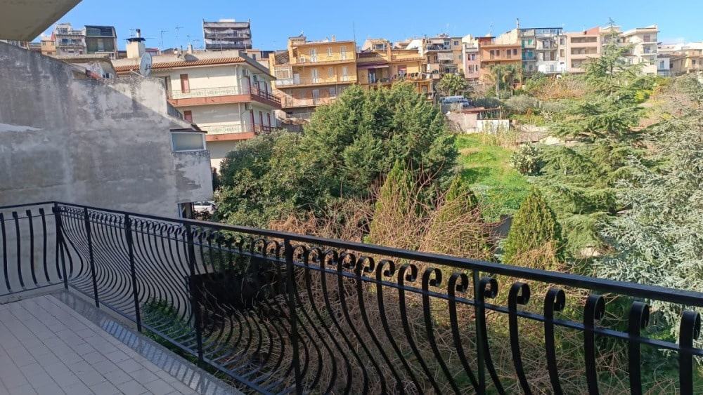 Balcone con vista sul verdeggiante quartiere urbano di Napoli, con alberi e edifici residenziali in background, perfetto per rilassarsi e godersi l'ambiente cittadino.