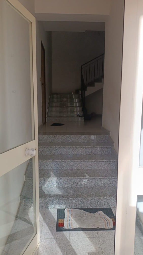 Scala interna con gradini in marmo in un appartamento, vista dall'ingresso, con ringhiera nera e ambiente luminoso.
